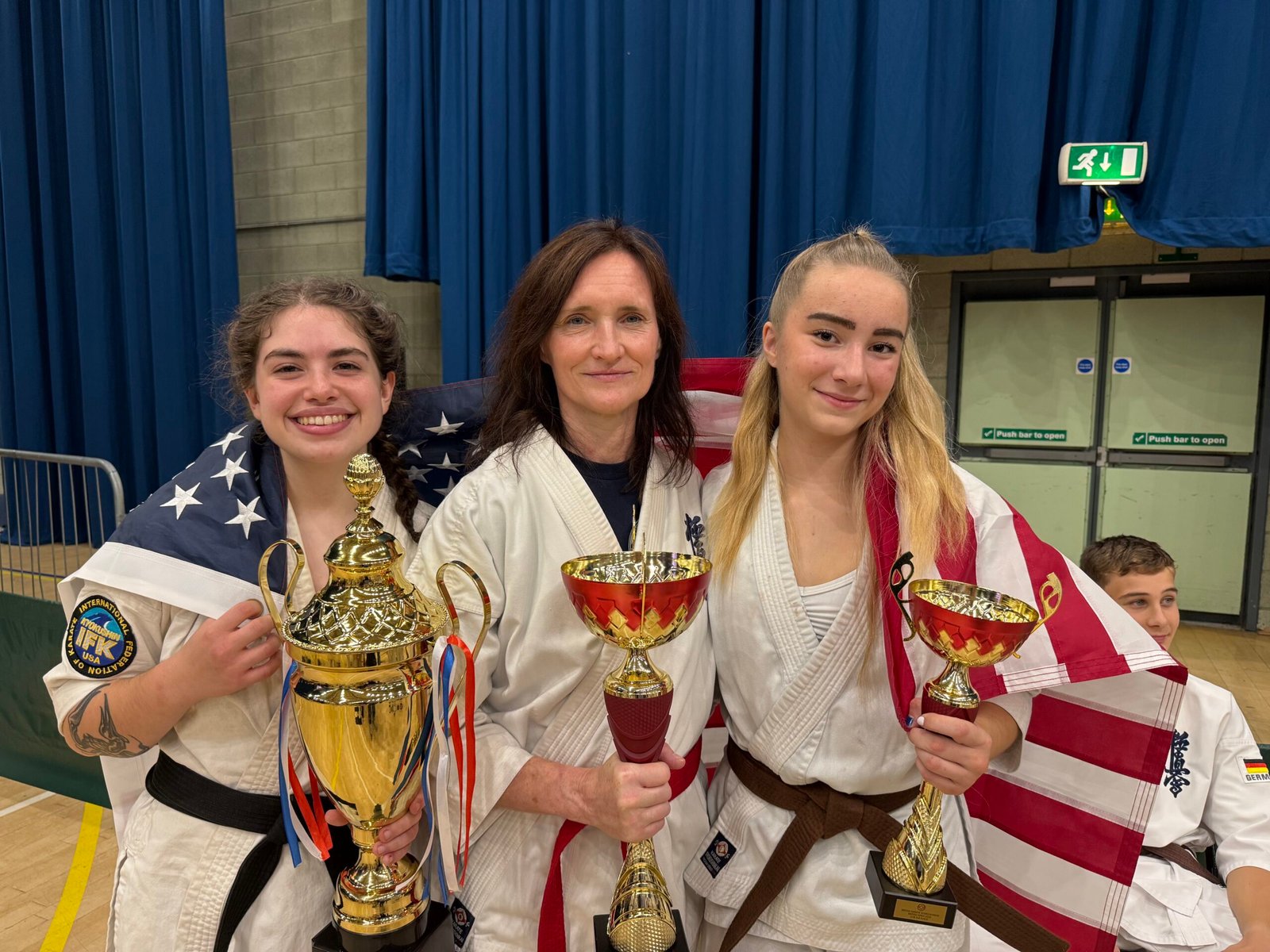 USA-IFK competitors Sensei Audrey Bartholomay, Elvira Anderson, and Willow Swan (left to right) display their trophies at the 48th BKK British Open in Crawley, England, 2026.